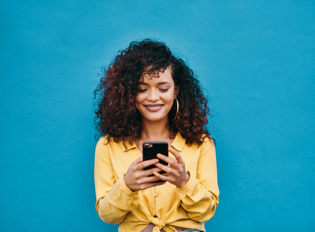 Une femme souriant devant son smartphone