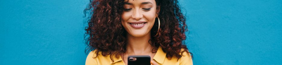 Une femme souriant devant son smartphone