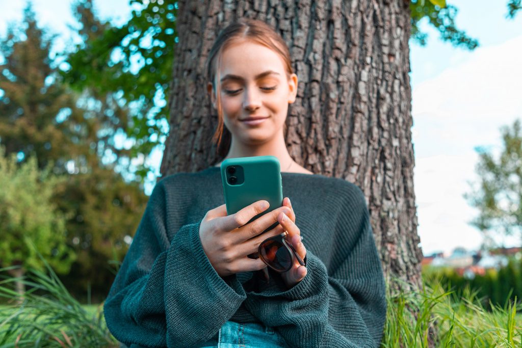 Une jeune femme souriant tout en regardant dans son smartphone