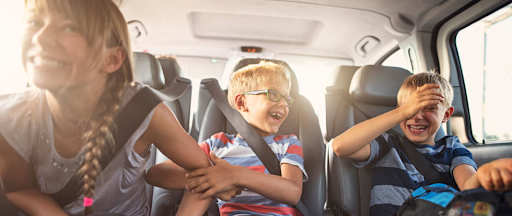 Des enfants en train de s'amuser entre eux dans une voiture sur la route des vacances