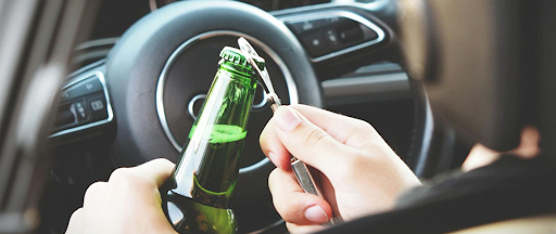 Un chauffeur en train d'ouvrir une bouteille de bière dans sa voiture