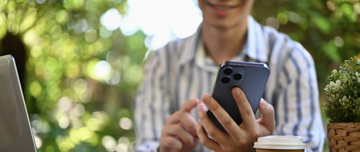 Une femme devant son ordinateur utilise son smartphone