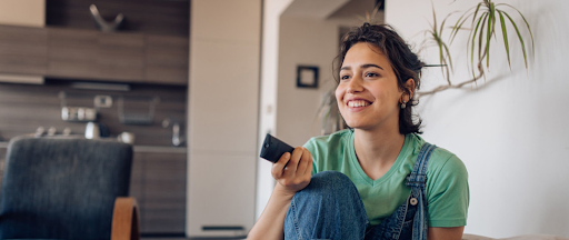 Une jeune femme en train de regarder la télé dans son salon.