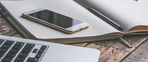 Smartphone sur un livre à côté d’un ordinateur portable